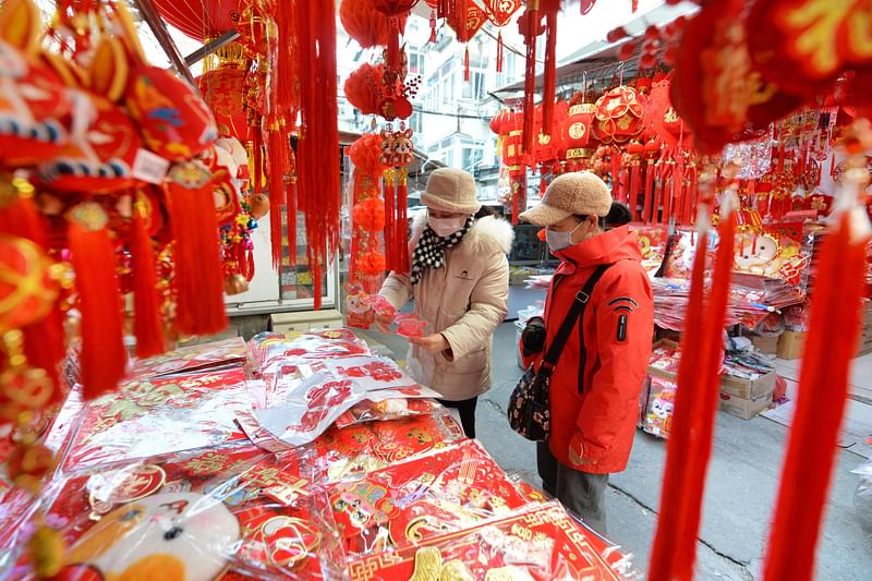 This photo taken on December 25, 2022 shows people buying decorations ahead of New Year's Day at a market in Qingdao, in China's eastern Shandong province