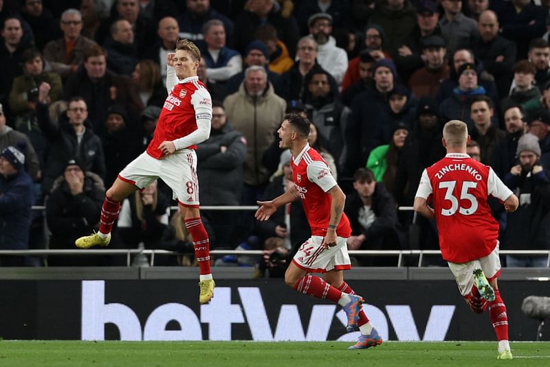 Arsenal's Norwegian midfielder Martin Odegaard (L) celebrates scoring the team's second goal during the English Premier League football match between Tottenham Hotspur and Arsenal at Tottenham Hotspur Stadium in London, on 15 January, 2023