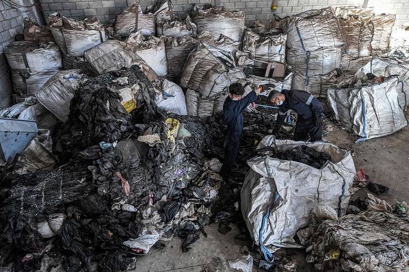 Workers sort through sacks of plastic waste at a workshop of the startup company "TileGreen", where it is recycled into eco-friendly interlocking tiles used in outdoor walkways, in the Ashir min Ramadan (10th of Ramadan) industrial city, about 60 kilometres east of Egypt's capital, on 8 December, 2022