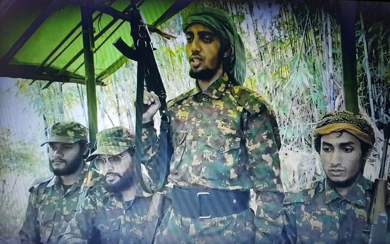 A screen grab from a video shows Jama'atul Ansar Fil Hindal Sharqiya military commander Shibbir Ahmed alias Hamid Karche wielding a firearm while Milon Talukdar (first from left), Saleh Ahmed (second from left) and Md Didar (right) are also seen.