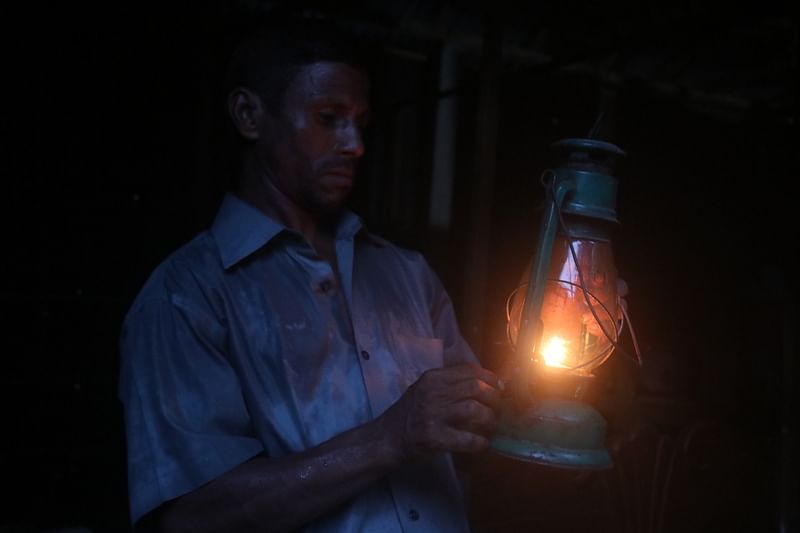 A man lights a kerosene lamp in his house as a power outage hits the area. The picture was taken from Uttam Baniapara, outskirt of Rangpur city, on 22 July 2022.