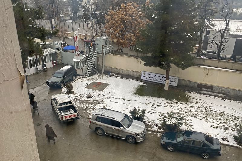 People walk past the parked vehicles after a suicide blast near Afghanistan's foreign ministry in Kabul on 11 January 2023.