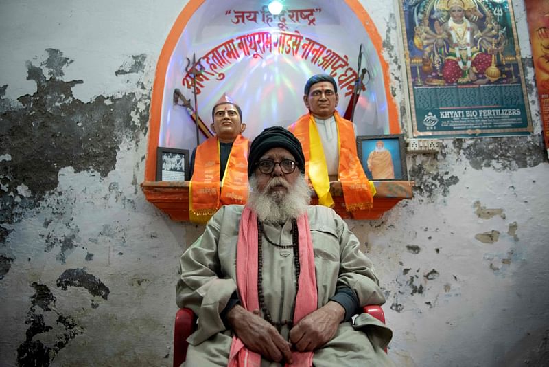 In this photograph taken on 
23 January, 2023, Hindu fundamentalist and priest Ashok Sharma sits in front of the statues of Mahatma Gandhi’s assassin’s Nathuram Godse (L) and Narayan Apte at Godse temple in Meerut