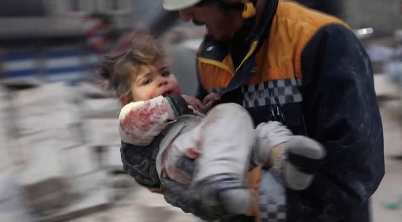 A rescuer carries a Syrian toddler, Raghad Ismail, away from the rubble of a building following an earthquake in rebel-held Azaz, Syria February 6, 2023 in this still image taken from video