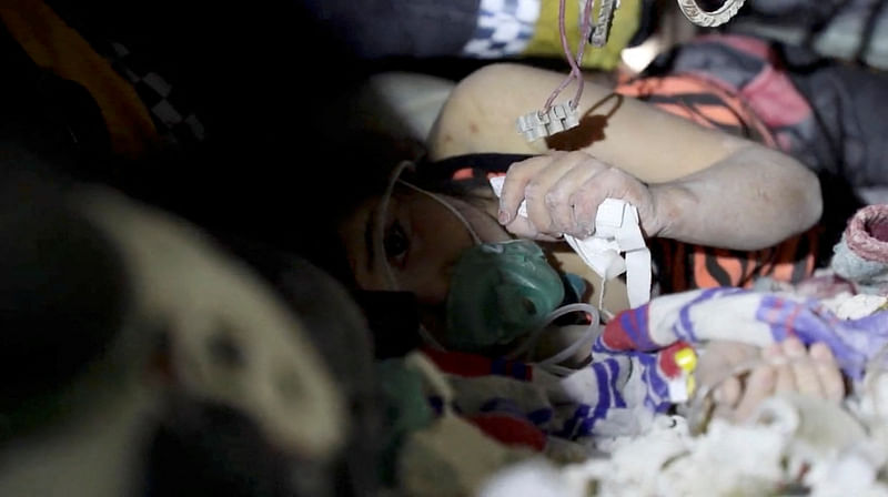 The White Helmet volunteers sing to a girl who is trapped under the rubble of a building during her rescue operation, in the aftermath of a deadly earthquake, in Idlib, Syria on 7 February 2023, in this still image obtained from a social media video.