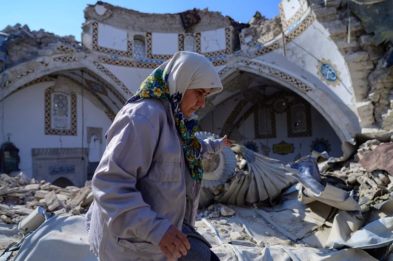 In this photograph taken on 12 February, 2023, a woman walks by the destroyed Habib-i Neccar mosque in the historic southern city of Antakya in Hatay, Turkey, a week after an earthquake devastated parts of Turkey and Syria leaving more than 35,000 dead and millions in dire need of aid.