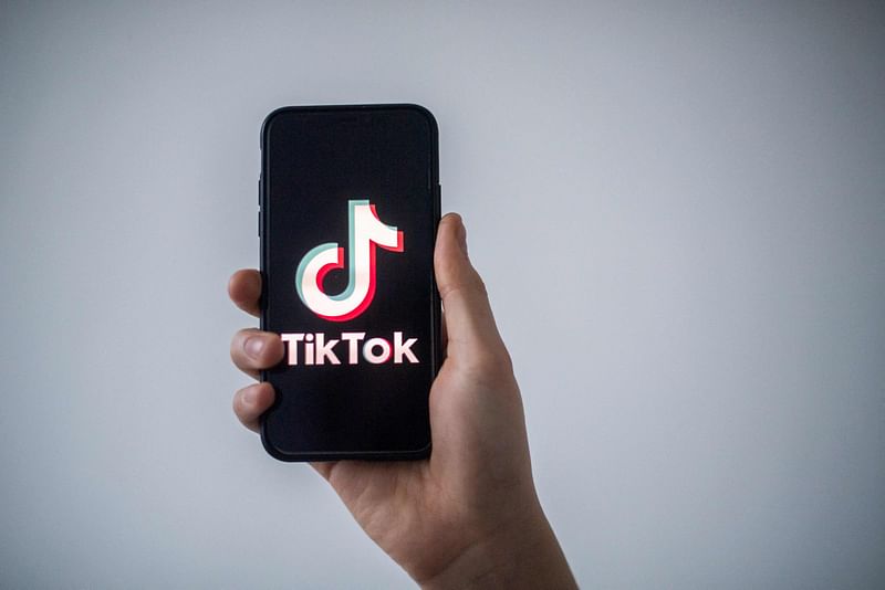 In this file photo taken on 21 January, 2021 in Nantes, western France, a man shows a smartphone with the logo of Chinese social network Tik Tok.