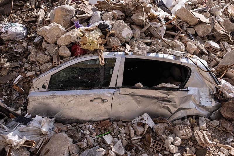 This photograph taken on 21 February, 2023, shows a destroyed car under the rubble of a collapsed building in Antakya, southern Turkey