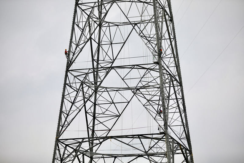 A worker climbs an under-construction power transmission tower in Munshiganj, outskirts of Dhaka, Bangladesh, on 30 June 2021