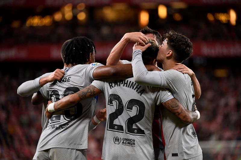 Barcelona's Brazilian forward Raphinha (back) celebrates with teammates scoring his team's first goal during the Spanish league football match between Athletic Club Bilbao and FC Barcelona at the San Mames stadium in Bilbao on 12 March, 2023