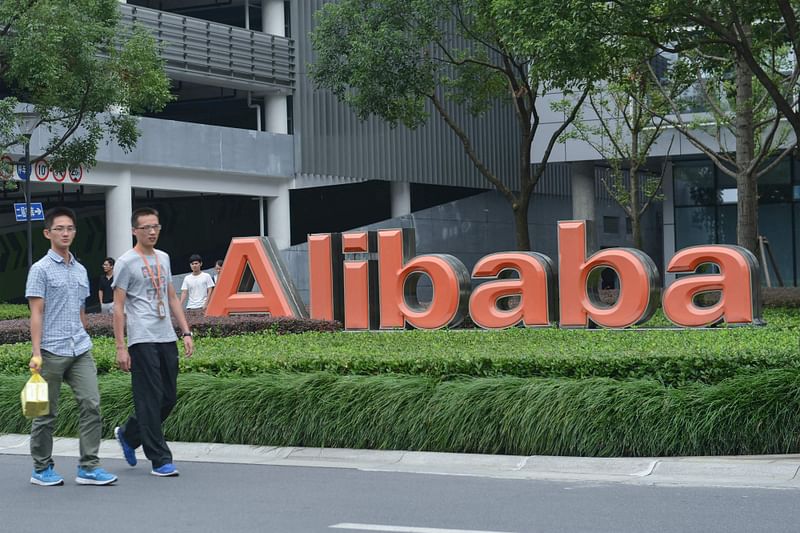 This file photo taken on 27 May, 2022 shows staff members walking past the logo of Chinese e-commerce giant Alibaba at its headquarters in Hangzhou, in China's eastern Zhejiang province. Alibaba announced on 28 March, 2023, that it would split into six individual business groups in one of the most significant overhauls of a leading Chinese tech firm to date.