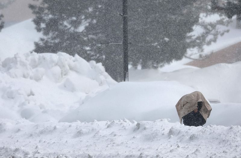 A person uses a jacket to protect their face from blowing snow as snow continues to fall in the Sierra Nevada mountains in the wake of an atmospheric river event on 
11 March, 2023