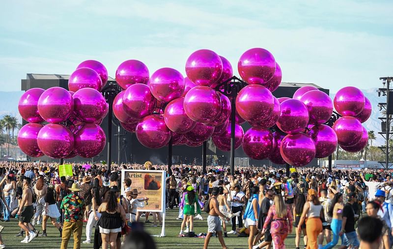 People walk by the "Molecular Cloud" installation by Vincent Leroy during the first weekend of the Coachella Valley Music and Arts Festival in Indio, California, on 16 April, 2023.