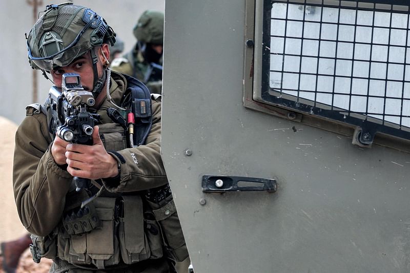 Israeli soldiers take aim behind a vehicle as they sweep an area during an army operation near the settlement of Elon Moreh in the occupied West Bank near Nablus on 11 April, 2023