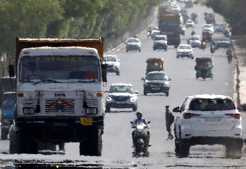 Traffic moves on a road in a heat haze during hot weather on the outskirts of Ahmedabad, India, May 12, 2022.