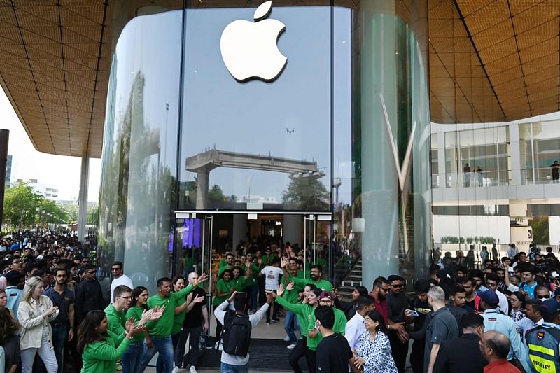 Apple employees (in green) cheer as they welcome customers during the opening of Apple's first retail store in India, in Mumbai on 18 April 2023.