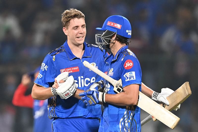 Mumbai Indians' Cameron Green (L) hugs teammate Tim David after their win in the Indian Premier League (IPL) Twenty20 cricket match between Delhi Capitals and Mumbai Indians at the Arun Jaitley Stadium in New Delhi on 11 April, 2023