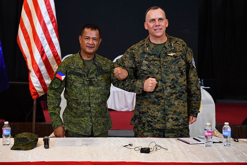 Philippine exercise director Major General Marvin Licudin (L) and US exercise director representative Major General Eric Austin (R) link arms during the opening ceremony of the 'Balikatan' joint military exercise at the military headquarters in Quezon City, suburban Manila on 11 April, 2023