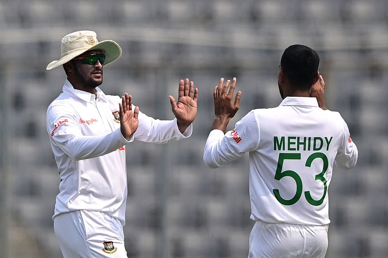 Bangladesh's Mehidy Hasan Miraz celebrates with his captain Shakib Al Hasan after taking the wicket of Ireland's Harry Tector during the first day of the Test between Bangladesh and Ireland at the Sher-e-Bangla National Cricket Stadium in Dhaka on 4 April 2023