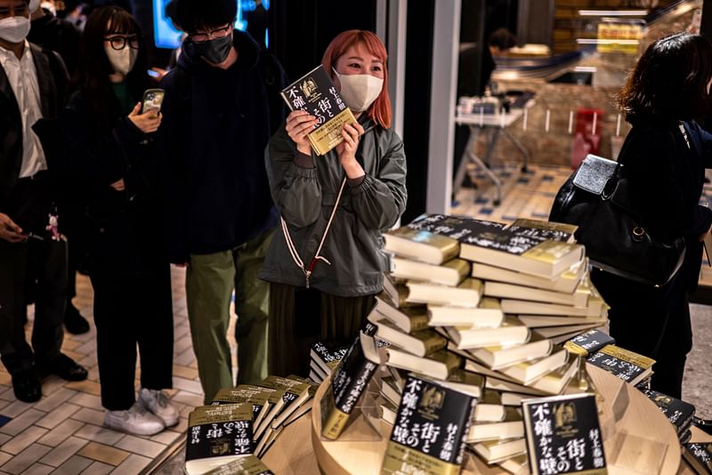 People line up to purchase the fresh copies of Japanese writer Haruki Murakami's new novella "The City and Its Uncertain Walls", which is the writer's new book in six years, at a book store in Shinjuku district of Tokyo early on 13 April, 2023