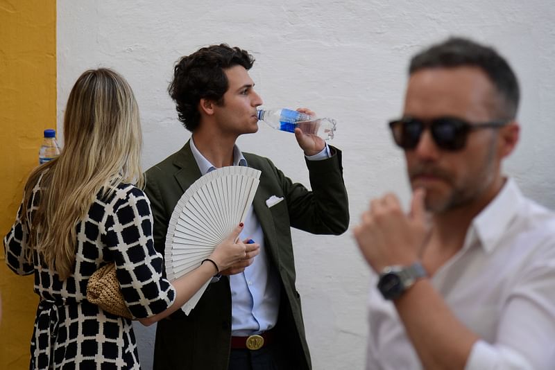 Visitors drink water as they arrive for the Feria de Abril bullfighting festival at La Maestranza bullring in Seville on 27 April 2023