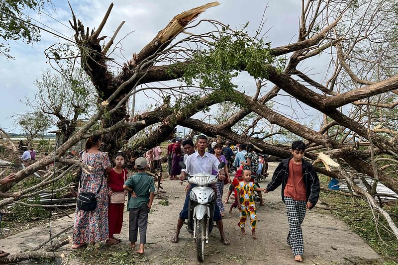 Residents walk past fallen trees in Kyauktaw in Myanmar's Rakhine state on 15 May, 2023, after Cyclone Mocha crashed ashore. The death toll from Cyclone Mocha that barrelled through Myanmar has reached 145 in the country, the junta's information team said in a statement on 19 May.