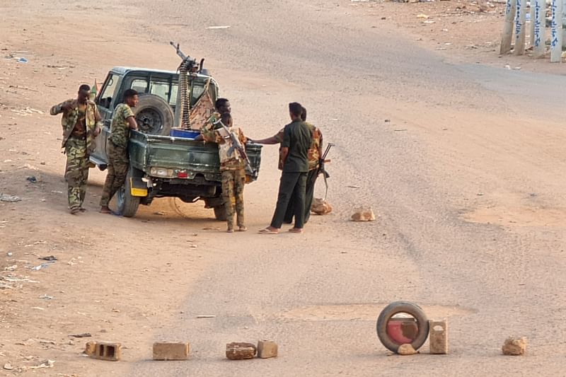 Soldiers of the Sudanese army stand near their vehicle on a road blocked with bricks in Khartoum on May 20, 2023, as violence between two rival generals continues