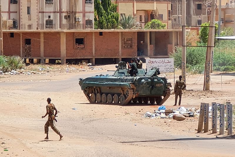 Sudanese Army sodliers walk near tanks stationed on a street in southern Khartoum, on 6 May, 2023, amid ongoing fighting against the paramilitary Rapid Support Forces. Air strikes battered Sudan's capital on 6 May, as fighting entered a fourth week only hours before the warring parties are to meet in Saudi Arabia for their first direct talks.