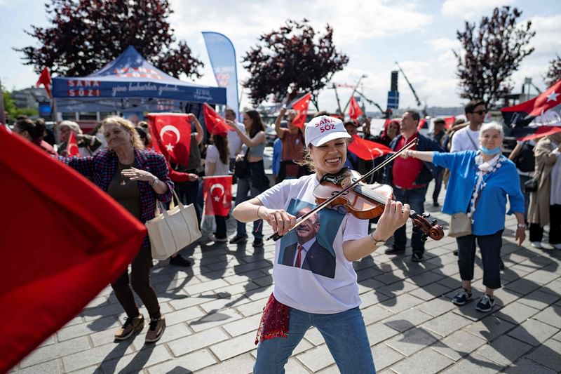 A supporter of the Republican People's Party (CHP) plays the violin as people listen ahead of the May 28 presidential runoff vote, in Istanbul on 27 May, 2023