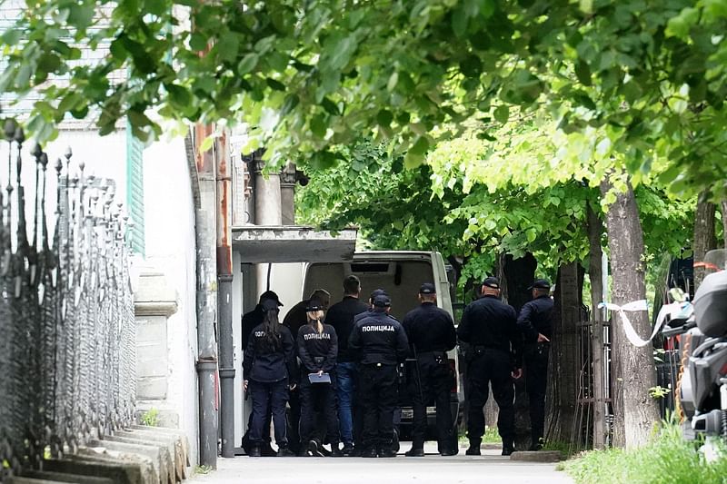 Police officers guard the school entrance as the bodies of the victims are loaded into a van following a shooting at a school in the capital Belgrade on 3 May 2023.