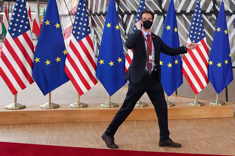 A security guard walks near EU and US flags, before the EU-US summit, in Brussels, Belgium on0 15 June, 2021.