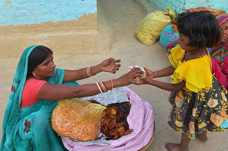 In this photograph taken on April 27, 2023, Jaimala Devi (L), mother-of-seven, sells snacks in a village in Darbhanga district of India's Bihar state