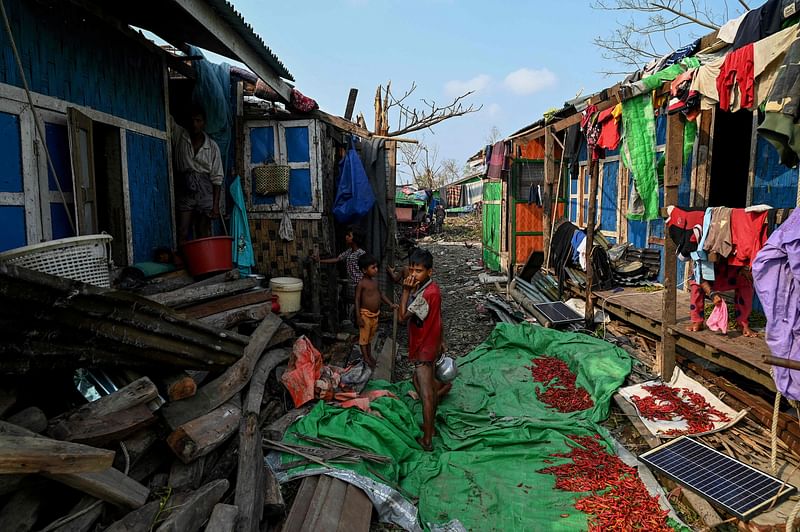 Rohingya children stand by destroyed houses at Ohn Taw Chay refugee camp in Sittwe on 16 May 2023, in the aftermath of Cyclone Mocha's landfall.