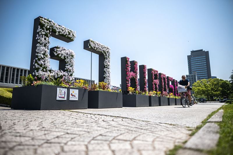 A man rides his bicycle past a "G7 Hiroshima" flower sign at the Peace Memorial Park in Hiroshima, ahead of the G7 Leaders' Summit, on May 17, 2023