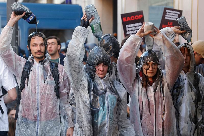 Climate protesters pour oil over them as scuffles between police and protesters broke out with the use of tear gas during a demonstration on the outskirts of the Paris venue for TotalEnergies Annual General Meeting in Paris on 26 May, 2023.