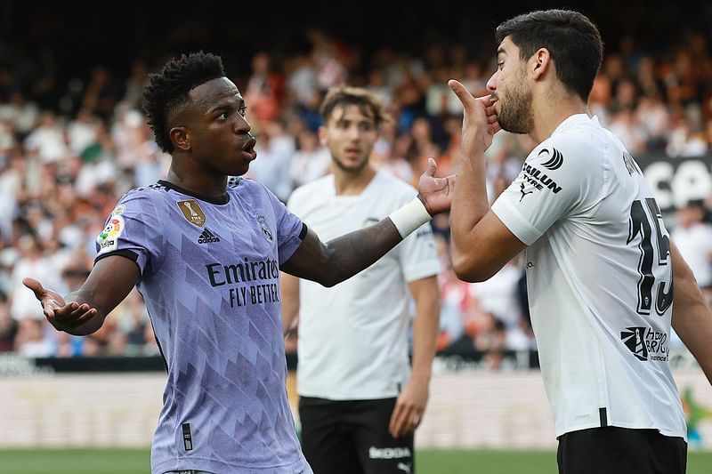 Real Madrid's Brazilian forward Vinicius Junior talks to Valencia's Turkish defender Cenk Ozkacar as he reacts to being insulted from the stands during the La Liga match between Valencia CF and Real Madrid CF at the Mestalla stadium in Valencia on 21 May 2023