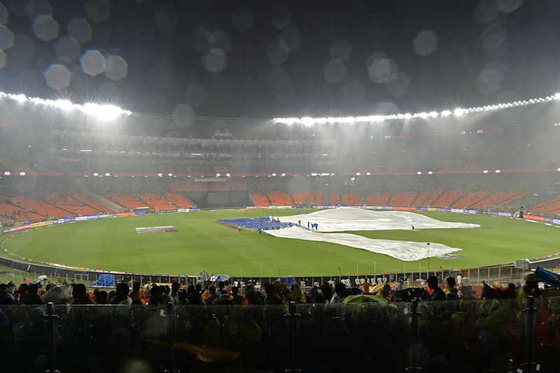 Ground staff cover the field as it rains during the Indian Premier League match between Gujarat Titans and Chennai Super Kings at the Narendra Modi Stadium in Ahmedabad on 29 May 2023