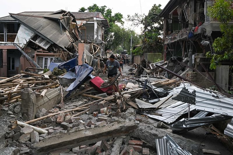 A woman walks through the wreckage of a building that was set on fire and vandalised by mobs in Khumujamba village on the outskirts of Churachandpur on 9 May, 2023, in a violence hit area of the north-eastern Indian state of Manipur