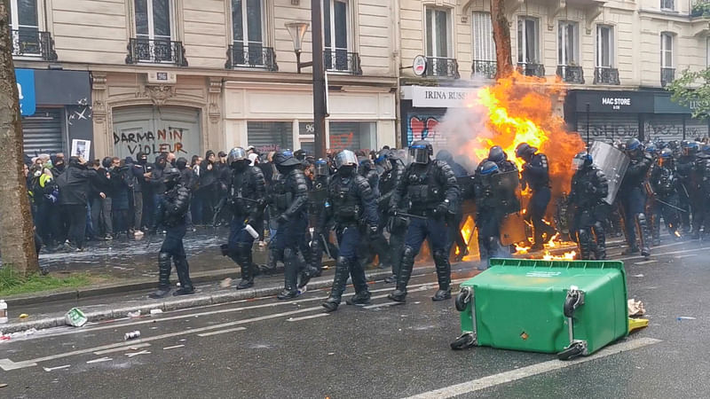 Riot police react to a petrol bomb burst, where an officer's gear caught fire, during May Day protests in Paris, France May 1, 2023 in this still image from social media video