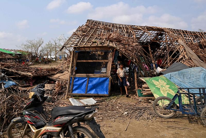 A boy walks out from a destroyed house at Ohn Taw Chay refugee camp in Sittwe on 16 May, 2023, in the aftermath of Cyclone Mocha's landfall.