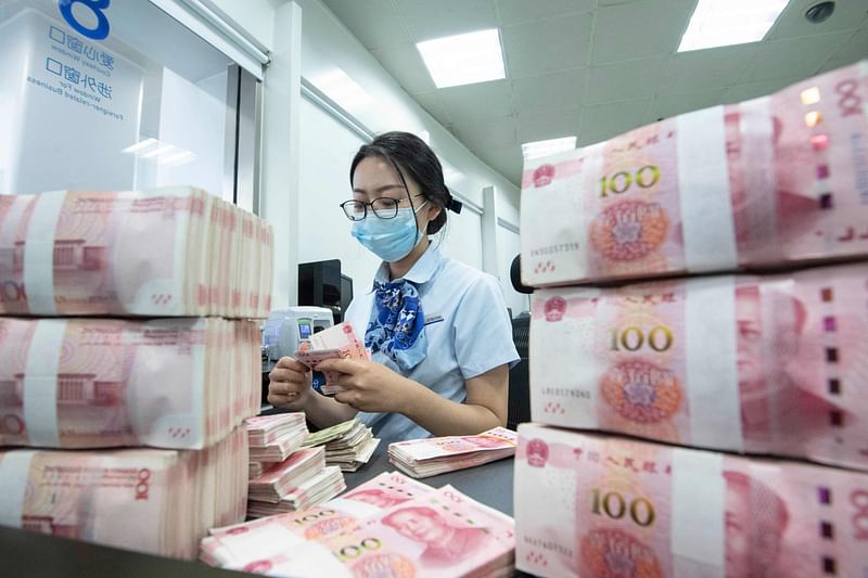 This photo taken on June 13, 2023 shows a bank employee counting 100-yuan notes at a bank counter in Nanjing, in China's eastern Jiangsu province.