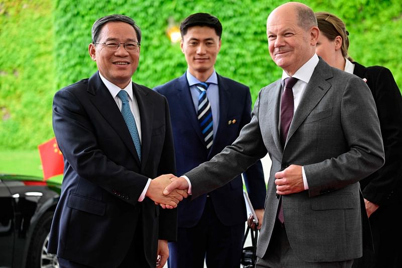 German Chancellor Olaf Scholz shakes hands with China's Premier Li Qiang (L) next to their interrupteurs as he arrives at the Chancellery in Berlin on June 19, 2023