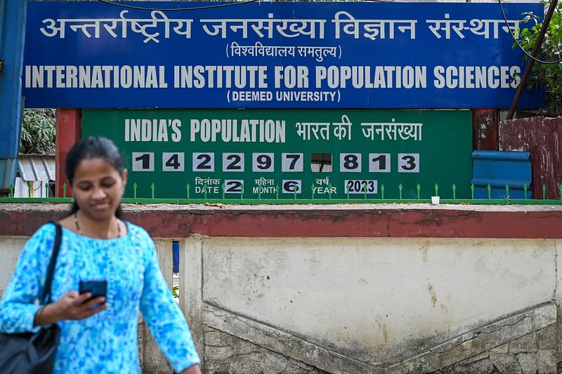 A pedestrian walks past a population clock board displayed outside the International Institute for Population Sciences (IIPS) in Mumbai on June 2, 2023