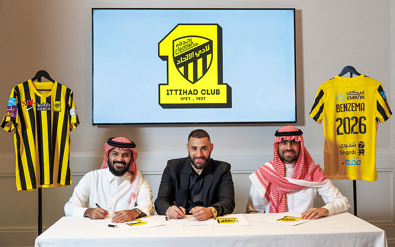 In this handout picture release by the Saudi Pro League on 6 June 2023, French footballer Karim Benzema sits between members of Saudi Arabia's Al-Ittihad club in Madrid during a signing ceremony in Madrid