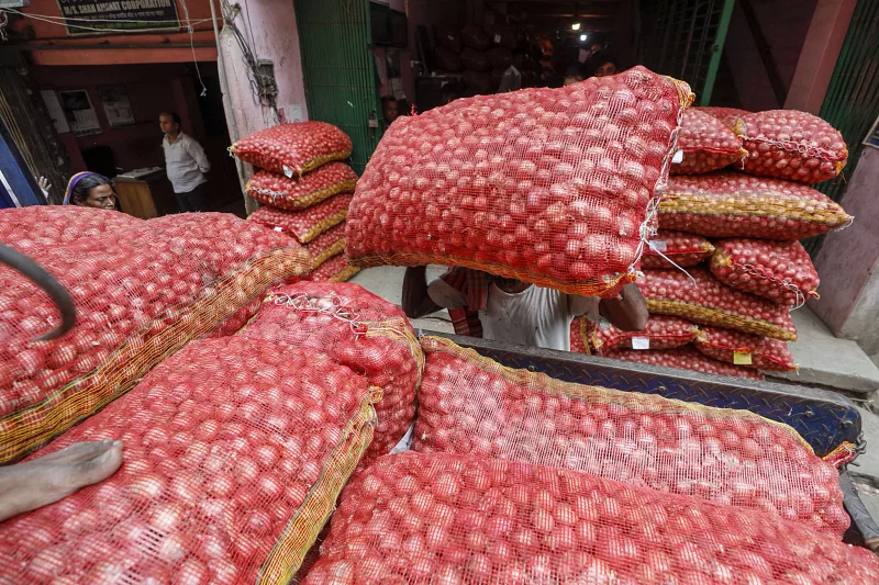 A worker loads a sack of onion on a truck on 3 June 2023