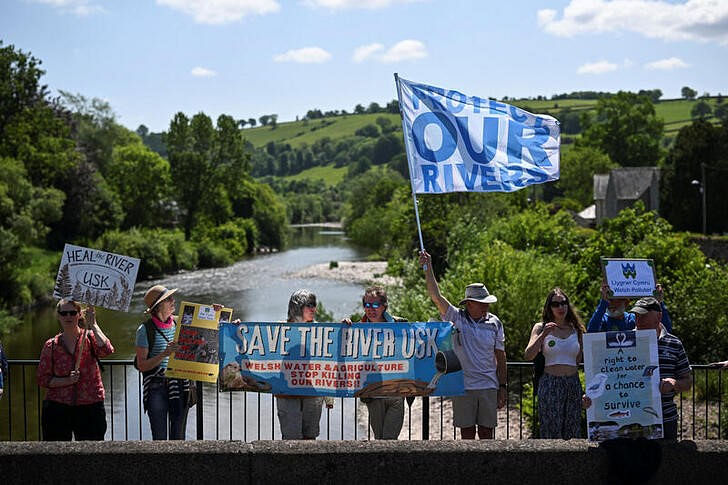 Activists take part in a protest, organised by water charity Save The River Usk, to demonstrate against poor agricultural farming practices and the continued dumping of untreated sewage by water companies, by the River Usk in Brecon, Wales, Britain, on 26 May, 2023