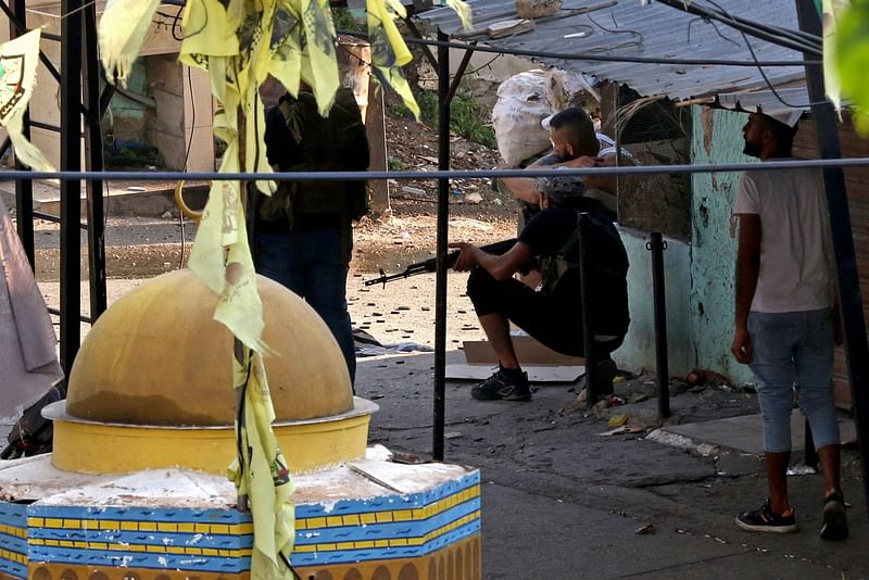 A militant takes cover amid clashes between Fatah movement and Islamists at the Ain al-Helweh Palestinian refugee camp in the southern coastal city of Sidon on July 30, 2023