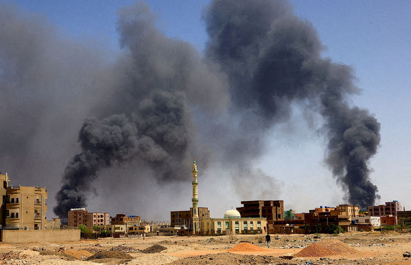 A man walks while smoke rises above buildings after aerial bombardments during clashes between the paramilitary Rapid Support Forces and the army in Khartoum North, Sudan, May 1, 2023