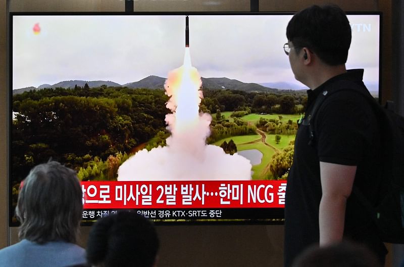 People watch a television screen showing a news broadcast with file footage of a North Korean missile test, at a railway station in Seoul on 19 July, 2023