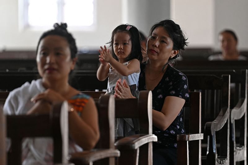 A woman along with her child attends the Children's Mass at Baptist Convention Center church in Imphal on 23 July, 2023. At least 120 people have been killed during months of ethnic conflict between the predominantly Hindu Meitei majority and the mainly Christian Kuki in India's troubled northeastern state of Manipur